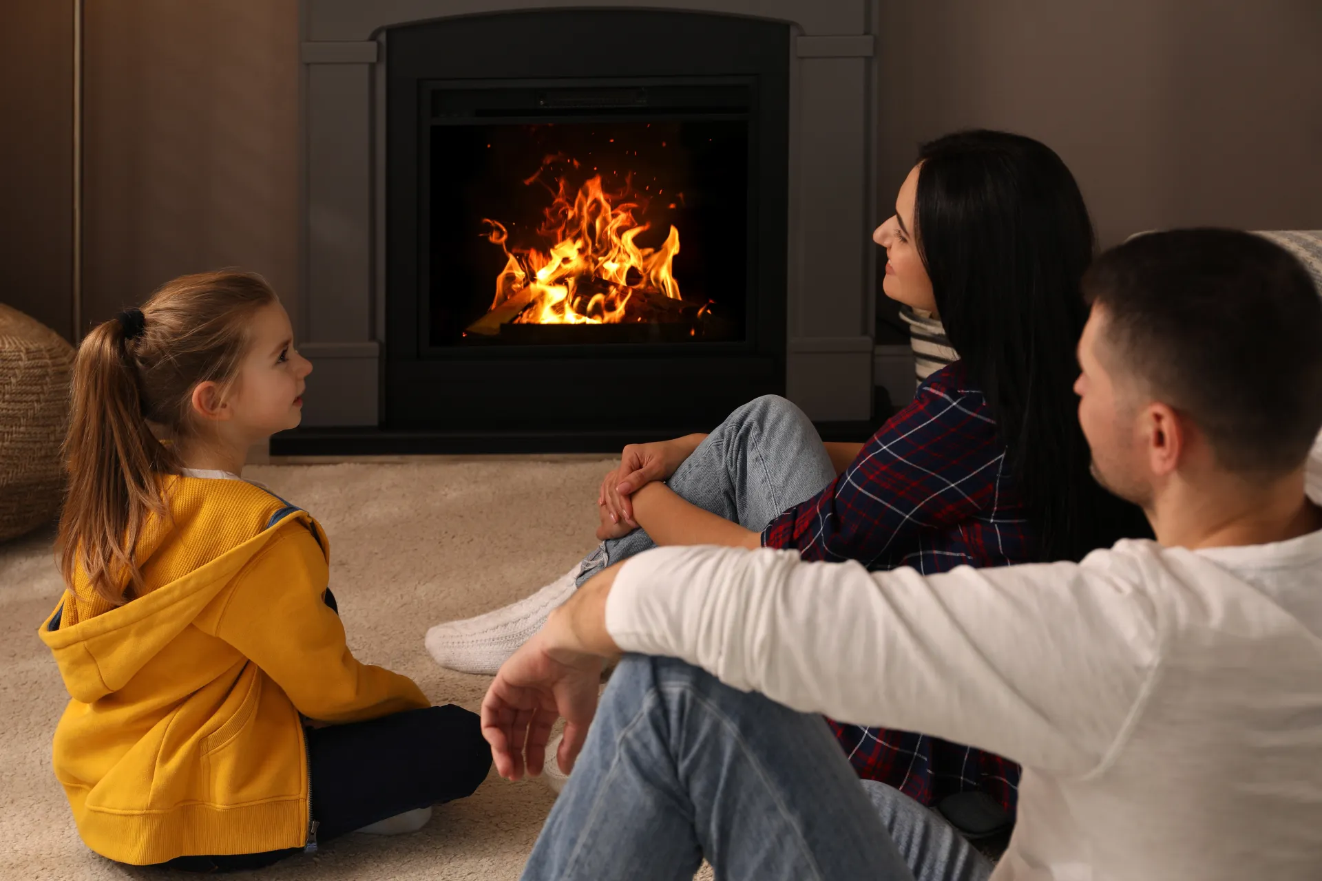 A family relaxing beside a warm gas fireplace at home in Frederick, Maryland